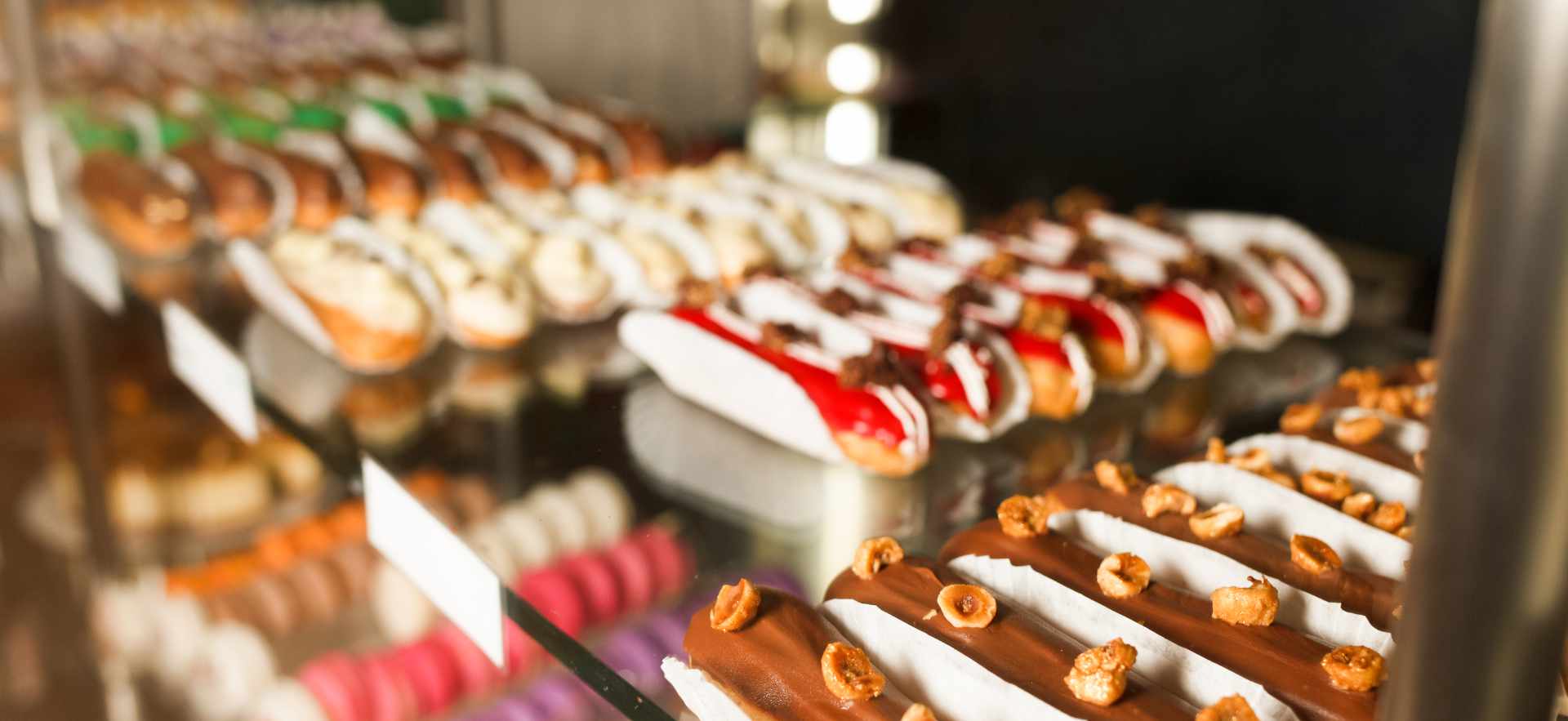 Large assortment of eclairs and other goodies on the shelf of a pastry shop